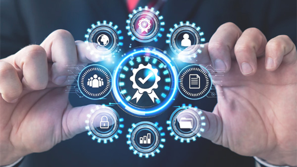 Nahaufnahme eines Geschäftsmannes in Anzug und Krawatte, der ein leuchtendes, digitales Diagramm mit einem zentralen Qualitätssiegel und umgebenden Symbolen für Prozesse, Sicherheit, Daten, Teamarbeit und globalen Zugriff hält.